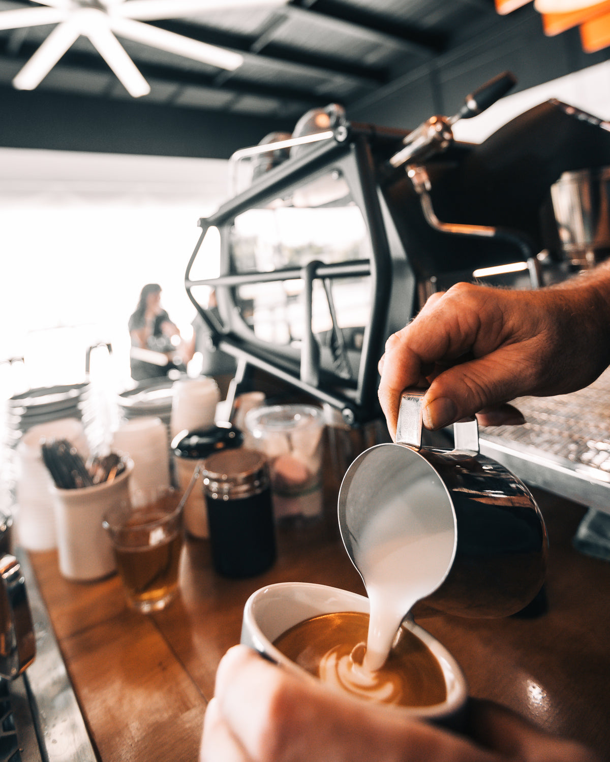 Barista pouring latte art at River City Coffee Roasters