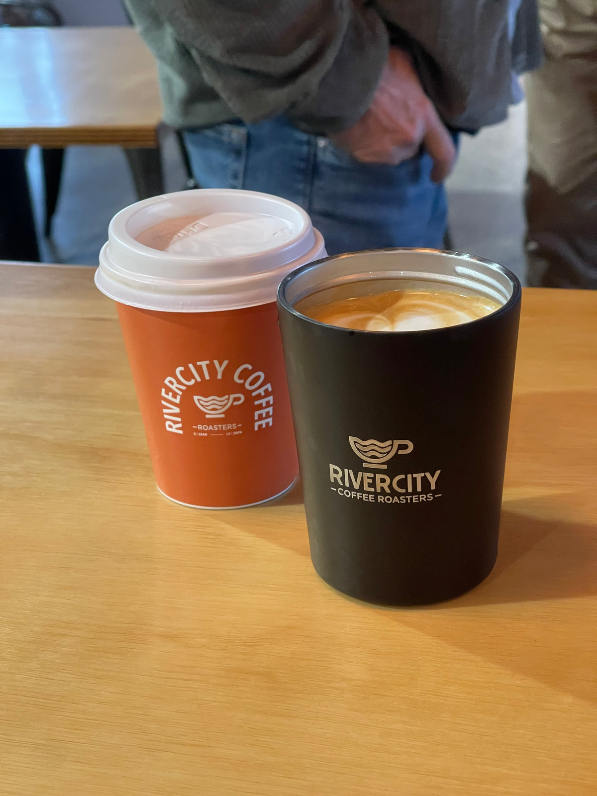 River City Coffee Roasters takeaway cup and reusable cup on the café bench