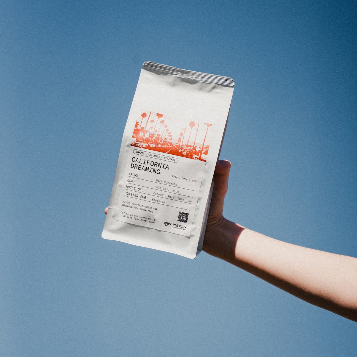 Bag of River City Coffee Roasters California Dreaming blend held up against a blue sky